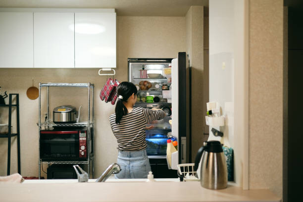 Woman wiping down refrigerator shelves with eco-friendly cleaner no off needed.