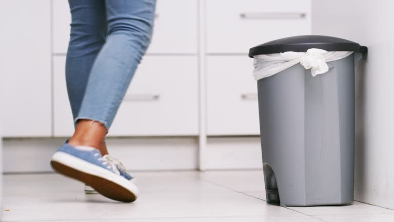 Person walking past a closed kitchen garbage bin, highlighting importance of cleanliness in odor control.